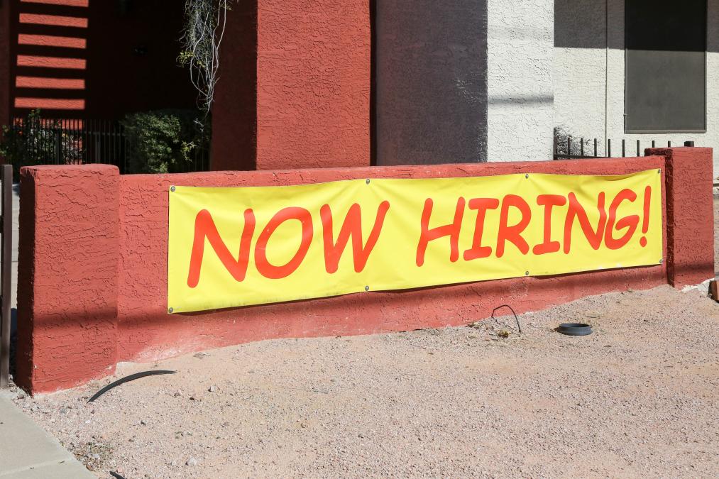 AZ: A Now Hiring Sign hangs outside to entice potential employees