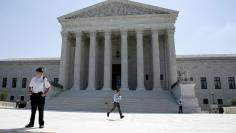 A television news assistant runs to his co-workers with printed copies of U.S. Supreme Court decisions at the court building in Washington