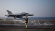 A U.S. Navy crew member looks at a F/A-18 Super Hornet fighter as it takes off from the USS Ronald Reagan during a joint naval drill between South Korea and the U.S., in the West Sea