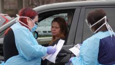 Healthcare workers with ChristianaCare test people with symptoms of the coronavirus in a drive-thru in the parking lot of Chase