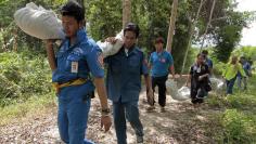 Rescue workers carry body bags with remains retrieved from a mass grave in Thailand's southern Songkhla province