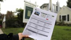 A woman holds a piece of paper advertising a home for sale in Santa Monica