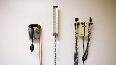 Devices used to take blood pressure, temperature, and examine eyes and ears rest on a wall inside of a doctor's office in New York