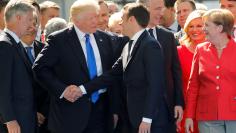 U.S. President Trump jokes with French President Emmanuel Macron about their handshakes in front of NATO leaders at the start of the NATO summit at their new headquarters in Brussels