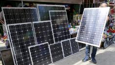 A vendor holds a piece of solar panel to attract buyers at a stall in Manila