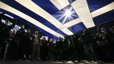 Protesters hold a giant Greek national flag during an anti-austerity and pro-government demonstration in front of the parliament in Athens