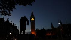 Dawn breaks behind the Houses of Parliament and the statue of Winston Churchill in Westminster, London, Britain