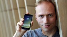 FILE PHOTO: Co-founder of Sweatcoin Oleg Fomenko poses with the app open on a phone at his London office