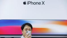 FILE PHOTO: An attendee uses a new iPhone X during a presentation for the media in Beijing, China October 31, 2017. REUTERS/Thomas Peter/File Photo