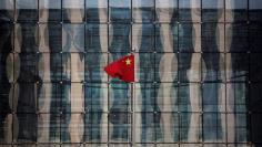 FILE PHOTO: A Chinese national flag flutters at the headquarters of a commercial bank on a financial street in central Beijing, China November 24, 2014.    REUTERS/Kim Kyung-Hoon/File Photo