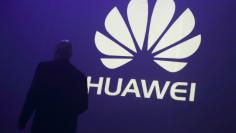 FILE PHOTO - A man walks past a logo during the presentation the Huawei's new smartphone, the Ascend P7, launched by China's Huawei Technologies in Paris, May 7, 2014.  REUTERS/Philippe Wojazer/File Photo