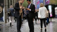 FILE PHOTO: Businessmen use their phones as they stand in the central business district (CBD) of Sydney in Australia, May 14, 2017. REUTERS/Steven Saphore/File Photo           