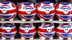 FILE PHOTO:Smiling Union Jack piggy banks are lined up for sale in the window of a souvenir store on Oxford Street in central London
