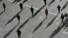People cast long shadows in the winter sunlight as they walk accross a plaza in the Canary Wharf financial district of London, Britain, January 17, 2018. REUTERS/Dylan Martinez  