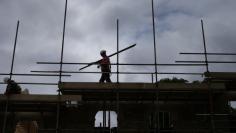 FILE PHOTO - A builder assembles scaffolding as he works on new homes being built for private sale on a council housing estate, in south London June 3, 2014. REUTERS/Andrew Winning