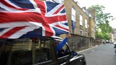 A taxi driver holds a Union flag, as he celebrates following the result of the EU referendum, in central London, Britain June 24, 2016.    REUTERS/Toby Melville  