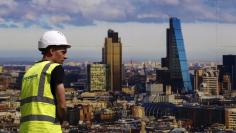 A worker walks past a picture of the London skyline outside the sales office of a property development in central London July 2, 2014. REUTERS/Luke MacGregor