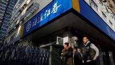 People walk past a branch of Haitong Securities, in Shanghai