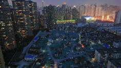 A night view of the old houses surrounded by new apartment buildings at Guangfuli neighbourhood in Shanghai, China, April 10, 2016. REUTERS/Aly Song 