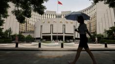 FILE PHOTO: Woman walks past the headquarters of the PBOC in Beijing
