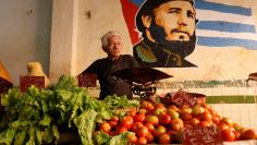 A man waits for clients inside a private vegetable market, next to an image of Cuba's late President Fidel Castro, in Havana, Cuba December 21, 2017. REUTERS/Stringer 