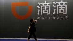 FILE PHOTO: A woman walks past Didi Chuxing's booth at the GMIC in Beijing