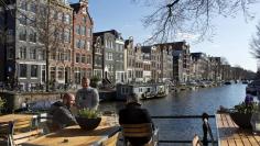 Men enjoy the afternoon sun at the Brouwersgracht canal in Amsterdam