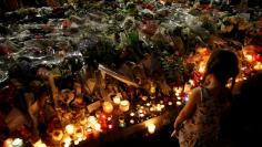 A child stands near flowers and burning candles placed to pay tribute to victims of the truck attack along the Promenade des Anglais on Bastille Day that killed scores and injured as many in Nice, France, July 17, 2016.  REUTERS/Pascal Rossignol