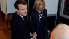 French presidential election candidate Emmanuel Macron (L), head of the political movement En Marche !, or Onwards ! and his wife Brigitte Trogneux hold hands after voting at a polling station during the the second round of 2017 French presidential elect