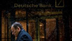 A man walks past the Deutsche Bank offices during a snow storm in Manhattan's financial district in New York January 21, 2014.   REUTERS/Brendan McDermid/File Photo
