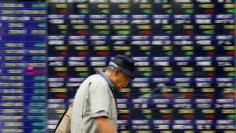 A man walks past an electronic stock quotation board outside a brokerage in Tokyo, Japan, September 22, 2017.   REUTERS/Toru Hanai - RC16074E2450