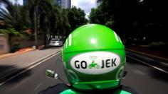 A Go-Jek driver rides a motorcycle on a street in Jakarta, Indonesia