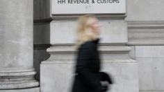FILE PHOTO - A pedestrian walks past the headquarters of Her Majesty's Revenue and Customs (HMRC) in central London