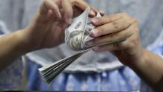 A teller counts U.S. dollars at a money changer in Jakarta, Indonesia