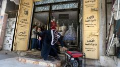 A Palestinian woman runs a generator outside a shop in the southern Gaza Strip January 8, 2018.  REUTERS/Ibraheem Abu Mustafa