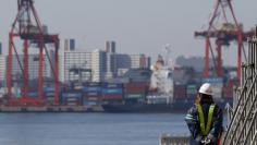 A worker walks near a container area at a port in Tokyo, February 19, 2015.   REUTERS/Toru Hanai