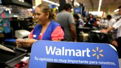 FILE PHOTO - A cashier smiles beyond a Walmart logo during the kick-off of the 'El Buen Fin' (The Good Weekend) holiday shopping season, at a Walmart store in Monterrey, Mexico, November 17, 2017. REUTERS/Daniel Becerril/File Photo