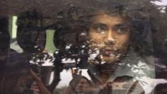 FILE PHOTO: Reuters reporter Kyaw Soe Oo looks out from a police vehicle as he leaves a court in Yangon, Myanmar, December 27, 2017. REUTERS/Stringer/File Photo