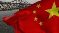 FILE PHOTO: A Chinese flag is seen in front of the Friendship bridge over the Yalu River connecting the North Korean town of Sinuiju and Dandong in China