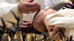 Pope Francis baptizes a baby during a ceremony in the Sistine Chapel at the Vatican