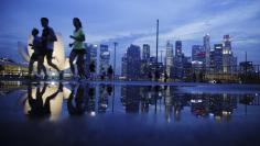 Joggers run past as the skyline of Singapore's financial district is seen in the background April 21, 2014. REUTERS/Edgar Su 