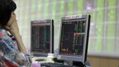 FILE PHOTO: A woman monitors stock market prices inside a brokerage in New Taipei city
