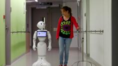 A woman walks with "Pepper" the robot at AZ Damiaan hospital in Ostend