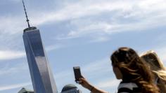 FILE PHOTO: A woman uses her phone to photograph One World Trade Center tower in New York, NY, U.S. on August 27, 2015. REUTERS/Brendan McDermid/File Photo