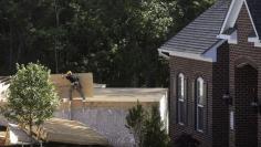 A lone carpenter carries plywood flooring next to a completed home (R) at a building site of Mid-Atlantic Builders' 'The Villages of Savannah' in Brandywine, Maryland May 31, 2013. REUTERS/Gary Cameron   