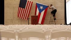 A worker takes off U.S and Puerto Rican flag after rally of U.S. Democratic presidential candidate Bernie Sanders in San Juan, Puerto Rico, May 16, 2016. REUTERS/Alvin Baez