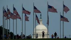 Flags fly at the Washington Monument as the U.S. Capitol is seen at rear on Flag Day in Washington