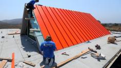 FILE PHOTO: Workers install a metal roof on the top of a single story family home being built in San Diego, California, U.S., July 17, 2017.   REUTERS/Mike Blake 