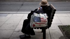 A homeless woman sits on a bench few blocks away from the White House in downtown Washington