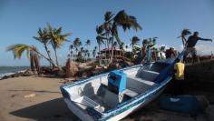 People recover items from a boat they found washed up on the shore, after Hurricane Maria hit the island in September, in Loiza, Puerto Rico October 26, 2017.  REUTERS/Alvin Baez